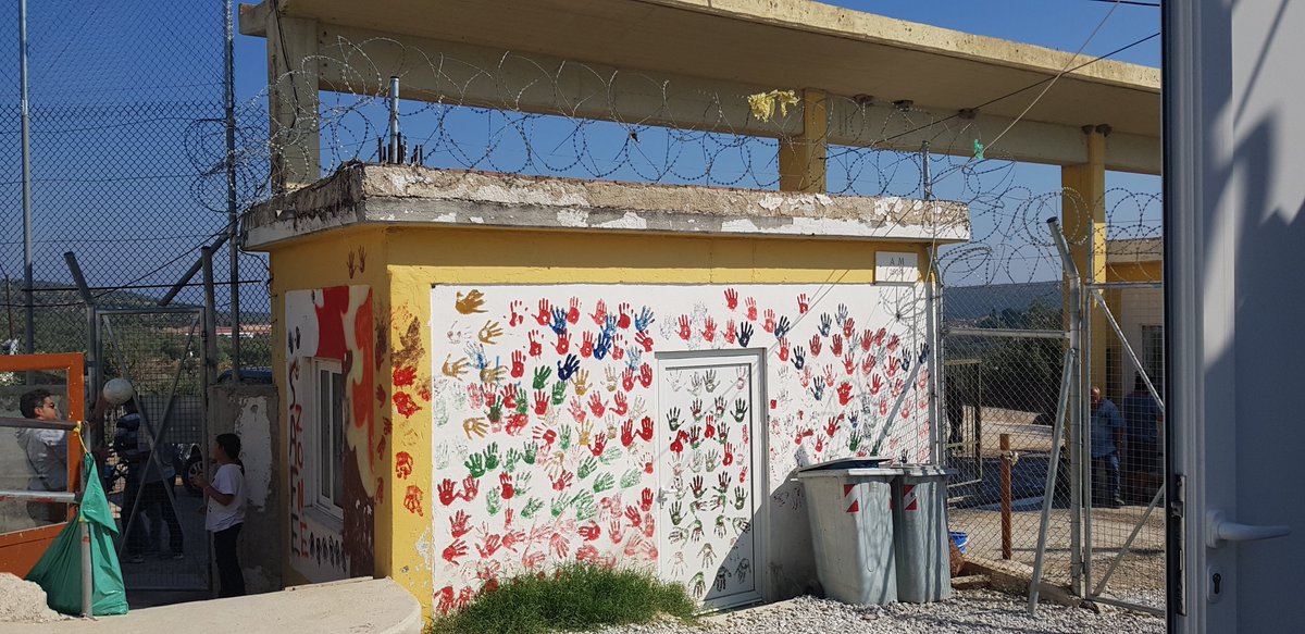 Building with child handprints surrounded by barbed wire