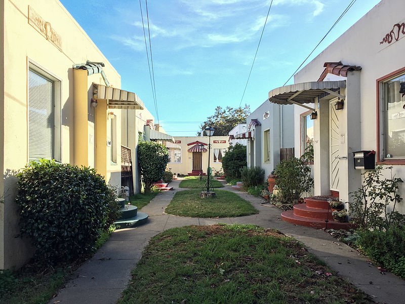 Not only are bungalow courts cheap to build, they're also smol and adorbs. This one's in Alameda, CA.Image by Jennvirskus,  https://commons.wikimedia.org/wiki/File:Example_of_a_bungalow_court_in_Alameda,_CA.jpg 9/