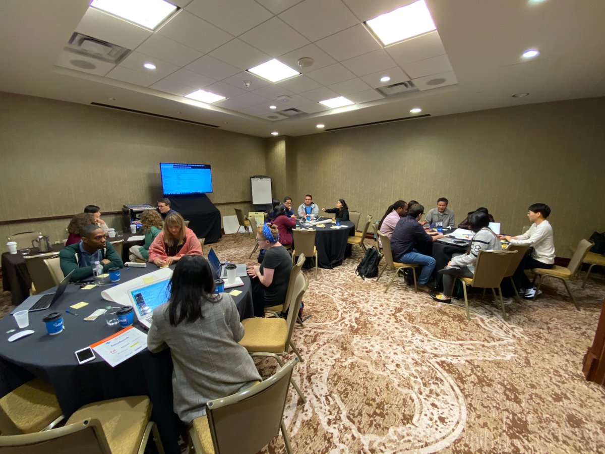 Four groups of people around tables engaged in discussion.