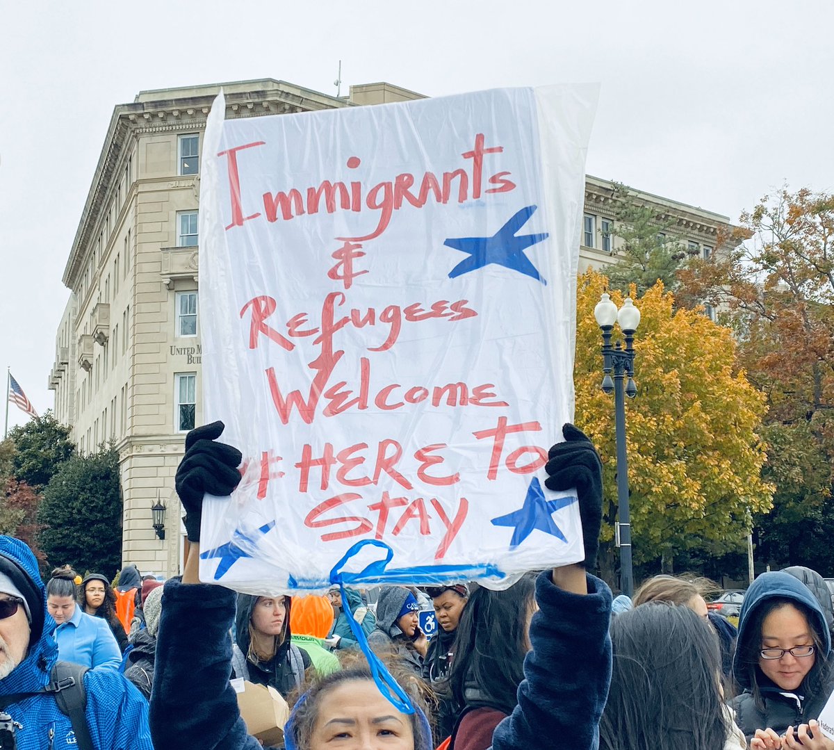 Sign says “immigrants and refugees welcome #heretostay.”