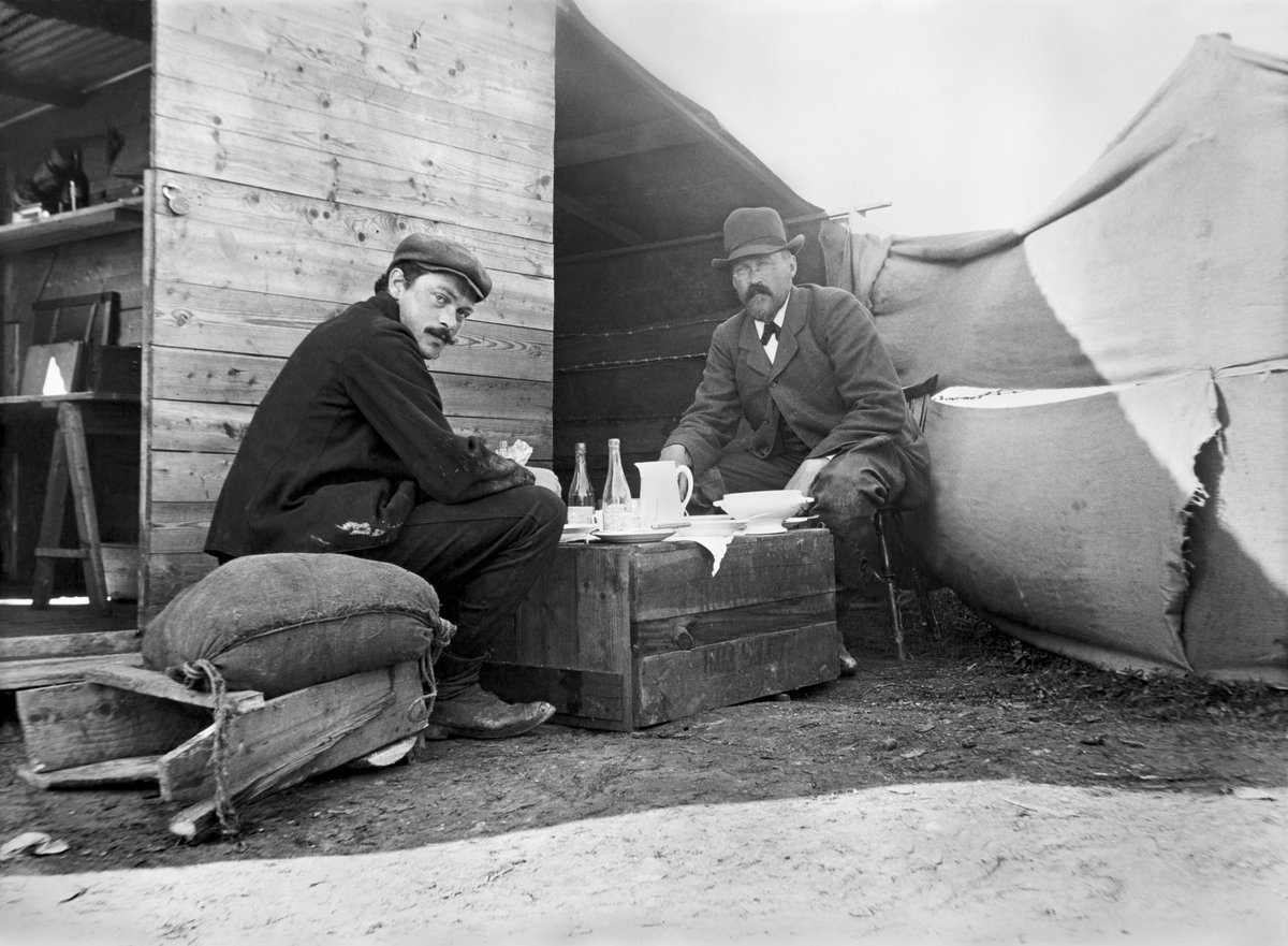 This is a picture of the archaeologists Haakon Shetelig (left) and Gabriel Gustafson (right) while taking lunch at the Oseberg dig in 1904.