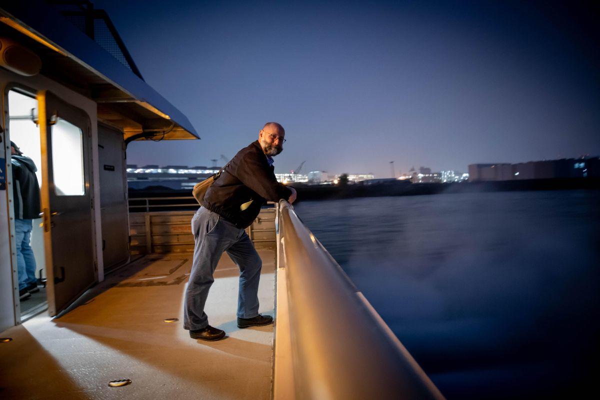 A man stands on the deck of a ferry 