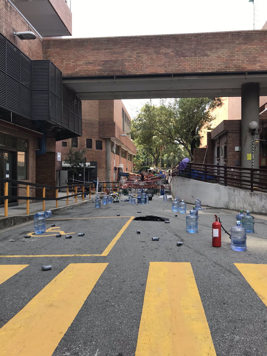 Layered security on the campus of PolyU. With every bridge fully blocked, Road access is controlled by a series of barricades separated by fields of bricks, nail and PVC caltrops and vegetable oil. Students perform bag checks on everyone entering to guard against undercover cops.