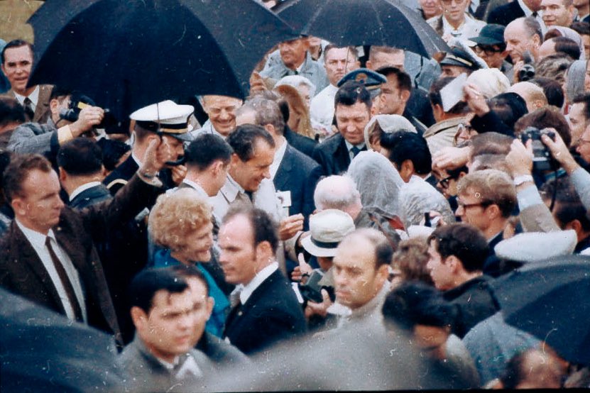 The umbrellas are out as Nixon (center) makes his way to the viewing stand. In the background can be seen ABC White House correspondent Tom Jarrell (far top left). 3/