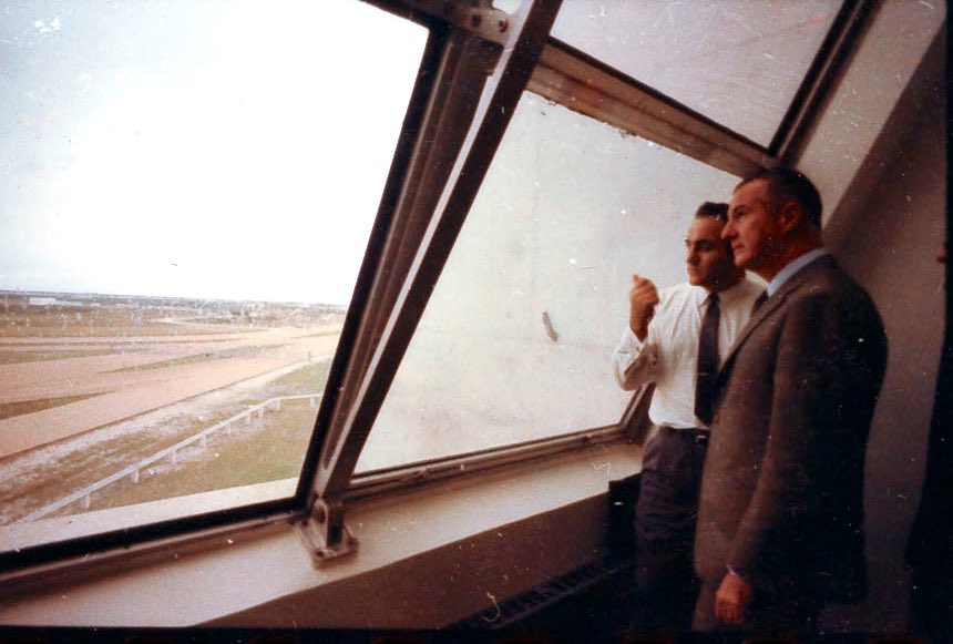 The sky begins to darken as the countdown nears the launch time of 11:22:00 a.m. EST. In the Launch Control Center Vice President Spiro Agnew discusses the weather with former launch operations director Rocco Petrone. 5/