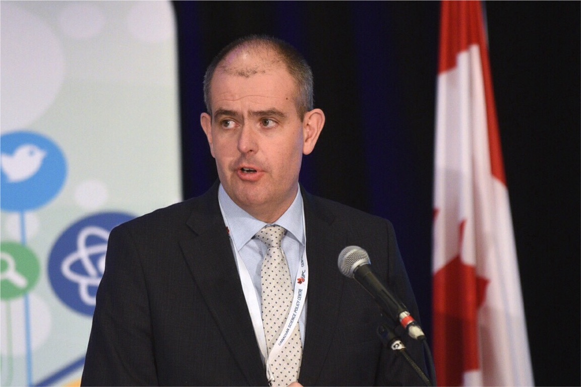 A person in front of a microphone addresses the audience.