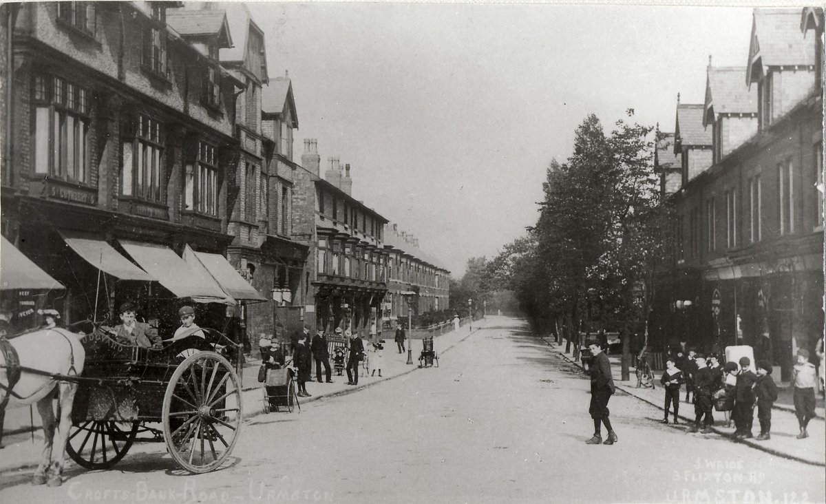 TraffordArchive's tweet photo. A view of Crofts Bank Road in #Urmston from the #railway bridge #c1910. Shops included Burgon's Ltd grocers, Henry Cuthbert butcher, Thomas M Titley jeweller & Martha Hobson stationer. https://t.co/i9d0TKTeIv
