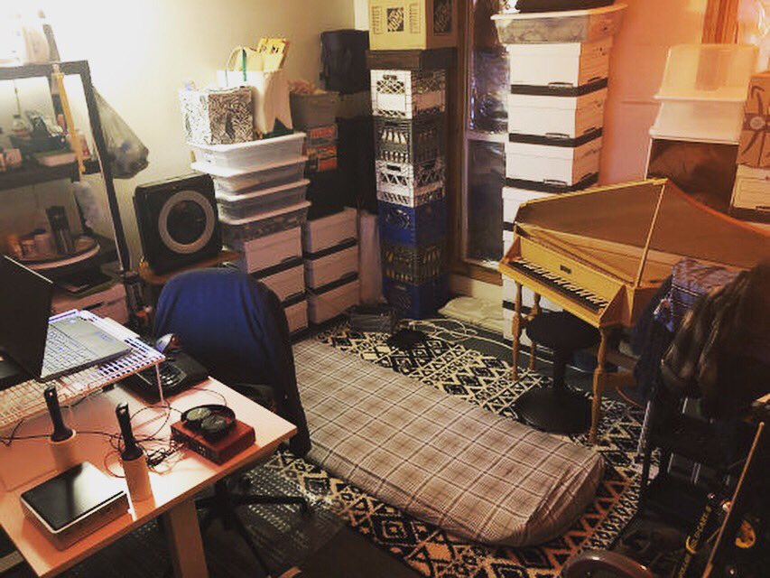 A room with a harpsichord, a small air mattress, and a lot of other things.