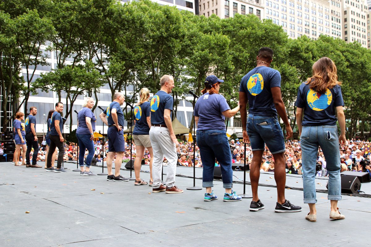 Photo taken of the cast of Come From Away singing with microphones 
