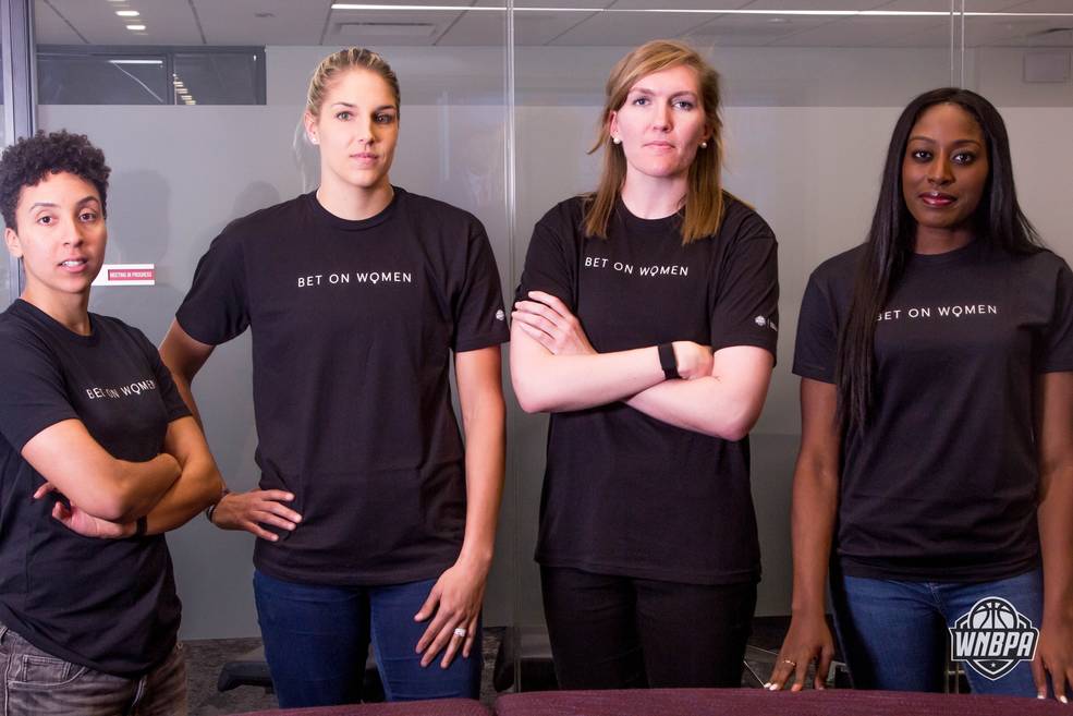 Four women athletes pose for a photo with serious expressions, each wearing a shirt that says "Bet on Women." 