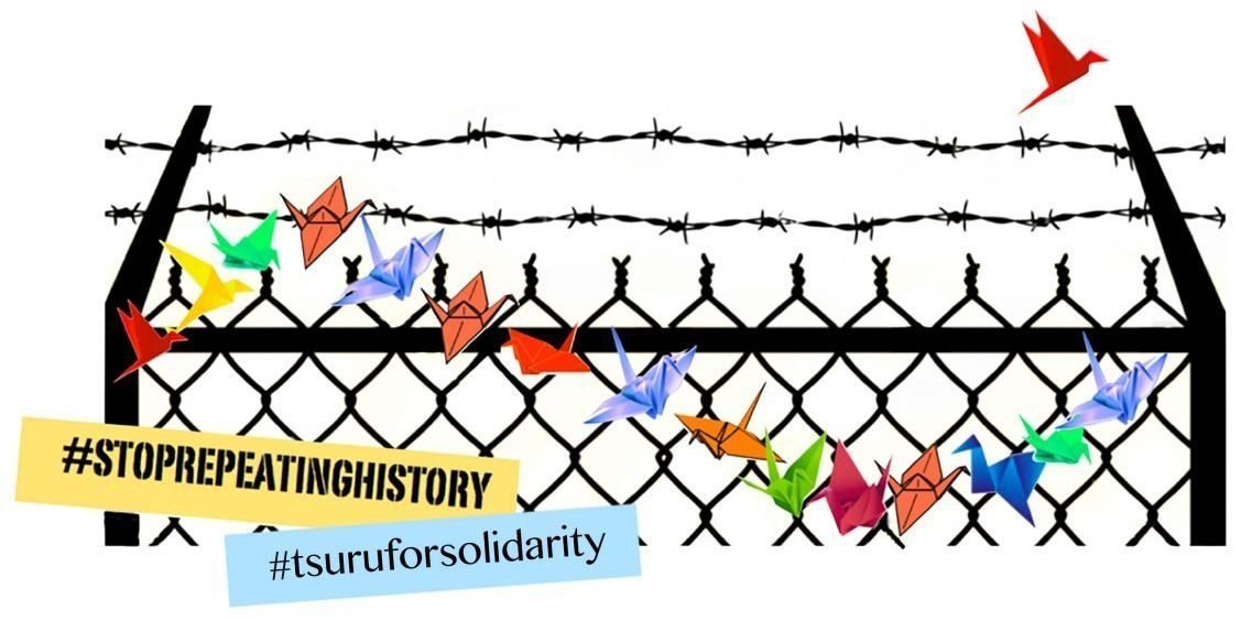 A string of multicolored paper cranes march in front of a barbed wire fence, with one red paper crane flying above the fenceline on the upper right. The words #STOPREPEATINGHISTORY and #tsuruforsolidarity appear on the lower lefthand side of the image.