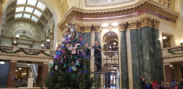 repschraa's tweet photo. The "Green Team" from Oakhill Correctional Center is hard at work, hanging ornanaments from school children on the capitol Christmas tree. https://t.co/tRWobQJsaN