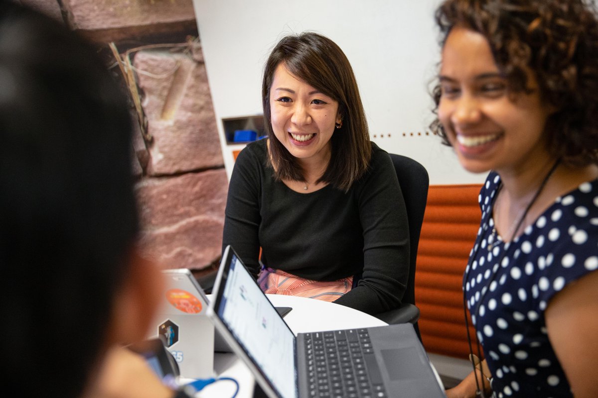Three people sat at a desk discussing business proposals. They all work in a startup and are thinking of ideas for how to grow their business.