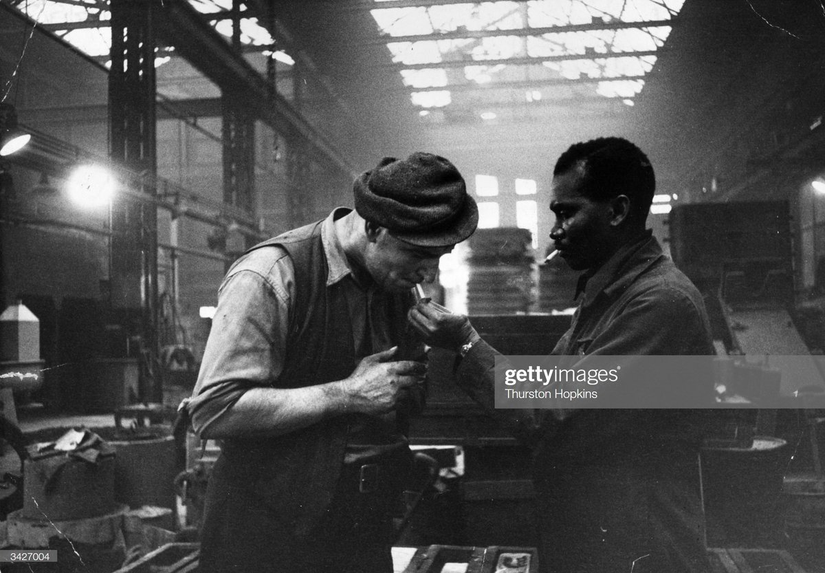 Jamaican immigrant Kwessi Blankson gives a light to workmate Jack White at The Phosphor Bronze Company where he is in charge of the oil-burners, 1955..Be like Kwessi and Jack..Photo by Thurston Hopkins