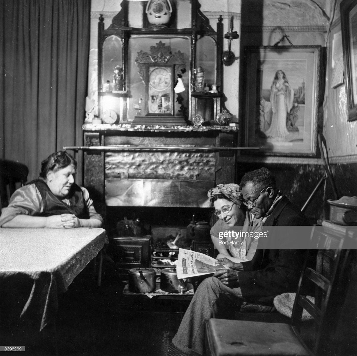 Mrs Lena Thornhill looks on as her daughter, Olive, reads the day's headlines with Edward Cousins, Cardiff, 1950.Photo by Bert Hardy