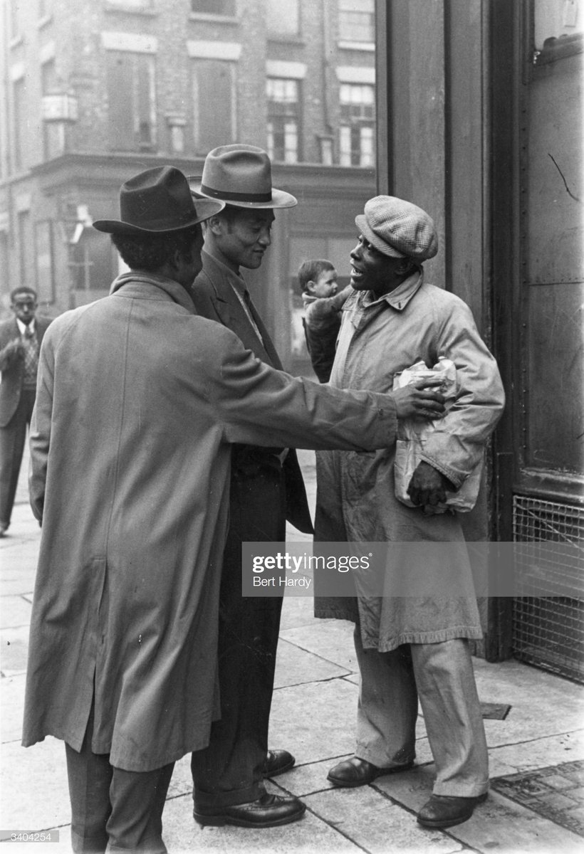 Three men talking in a Liverpool street, 1949. Photo by Bert Hardy