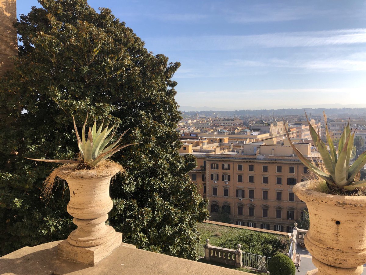 The outside balcony of The Vatican Museum. It brilliantly shows a glorious view of the city of Rome, & it is nicely accompanied by the plants that reside within the flower pots made out of stone, while The Sun shines greatly above. How relaxing.