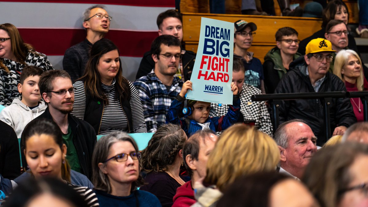A young girl holds up a "Dream Big Fight Hard" sign at the Manchester town hall.