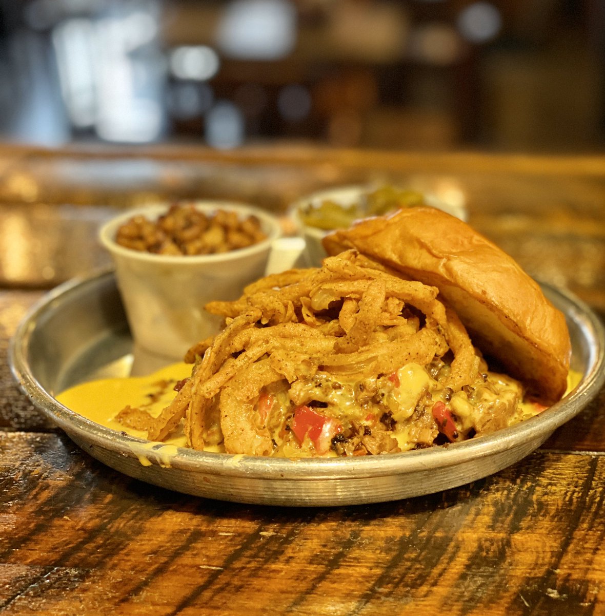 Edleysbbq's tweet photo. Our East Nashville location is making a special today called the “Take It Cheesy”. Brisket cheesesteak topped with onion straws. Bet you can’t guess what the staff are eating on break today? #BBQ #BBQLife #EdleysBBQ https://t.co/0t2q10x6FV