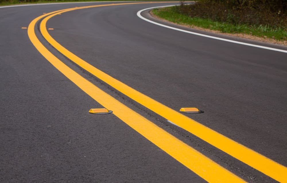 A Double Continuous Yellow line implies that crossing the line is strictly not permitted for either side. So that implies no overtaking, no U-turns or no lane changes. This is where probability of accident is highest so stick to ur lane.