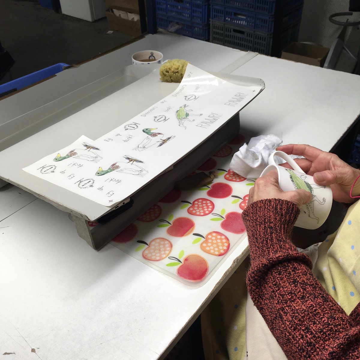 Mug delivery today! 📦 Did you know that my mugs are all hand decorated in Stoke-on-Trent? Here’s the proof, one of the lovely ladies at <a href="/heraldicpottery/">Heraldic Pottery</a> applying the dinosaur transfer before they head to the kiln to get fired and fixed.  🙌🏻 #madeinstoke #mugs #deathbytea