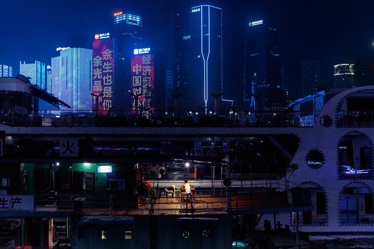 Photography by Liam Wong of Chongqing, China at night. Two men can be seen on the entrance of a large cruise ship - taken at midnight.