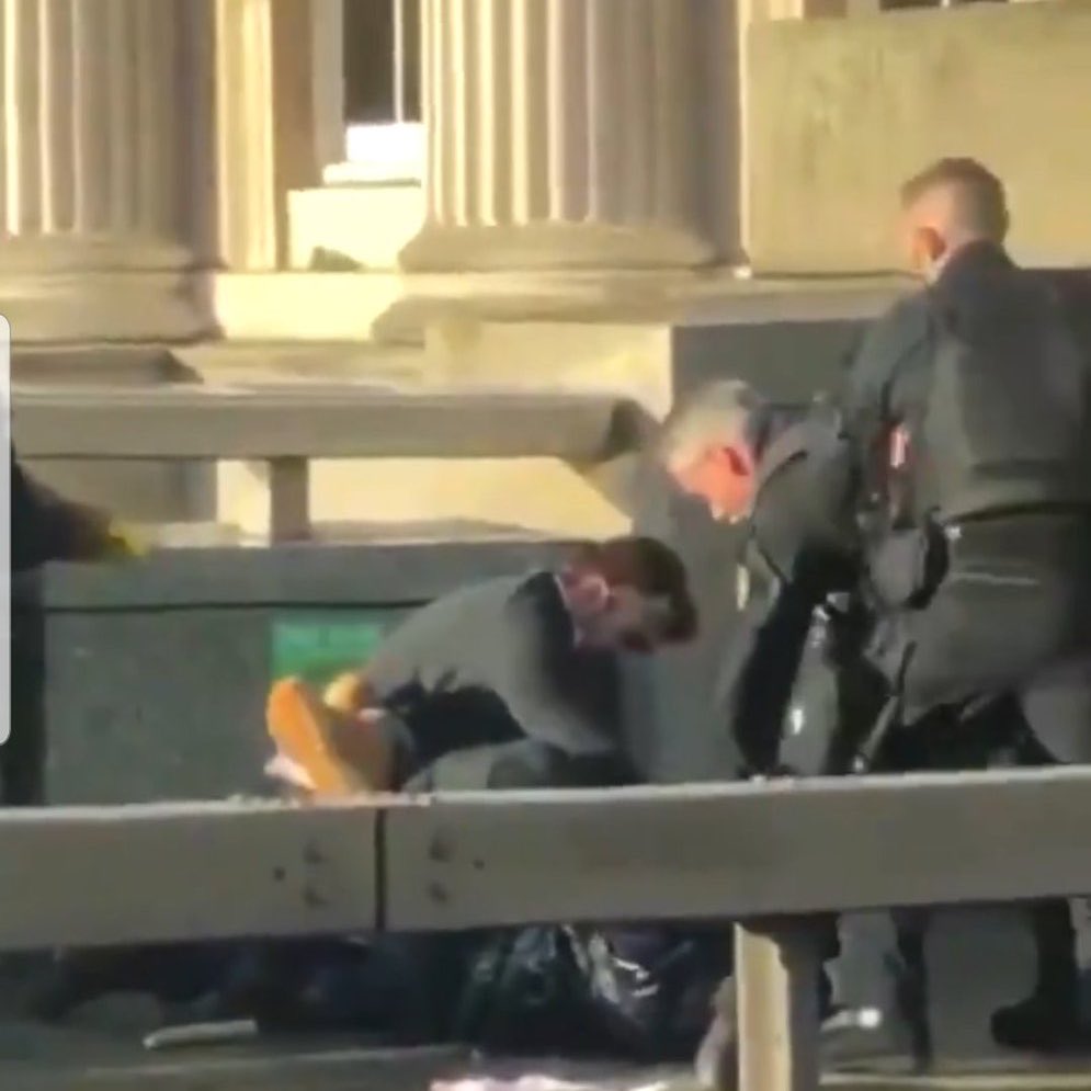 A civilian and 2 police officers struggling with the terrorist suspect