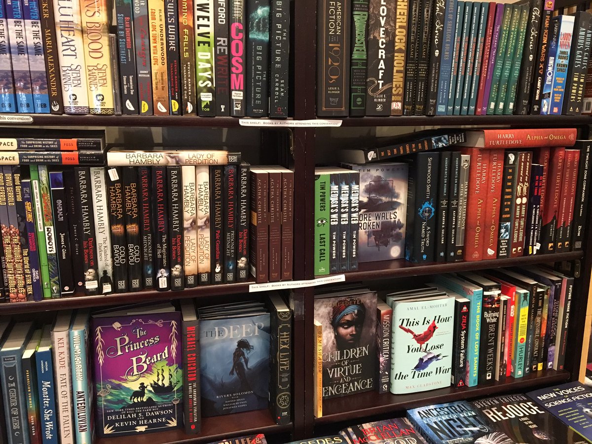 BookUniverse's tweet photo. @tithenai Not art, but here’s the book (lower shelf, face-out) in my #LosCon46 dealer display... 😺📚 https://t.co/GEeKtPcTqZ