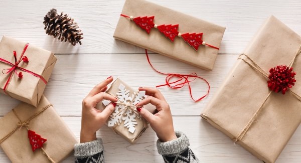 closeup of hands wrapping holiday gift boxes