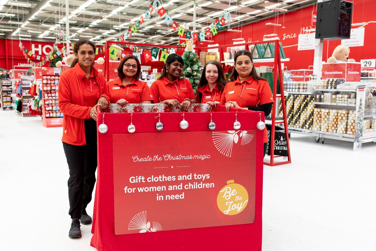 five women wearing The Warehouse uniforms standing behind a decorated donation box inside a The Warehouse store.