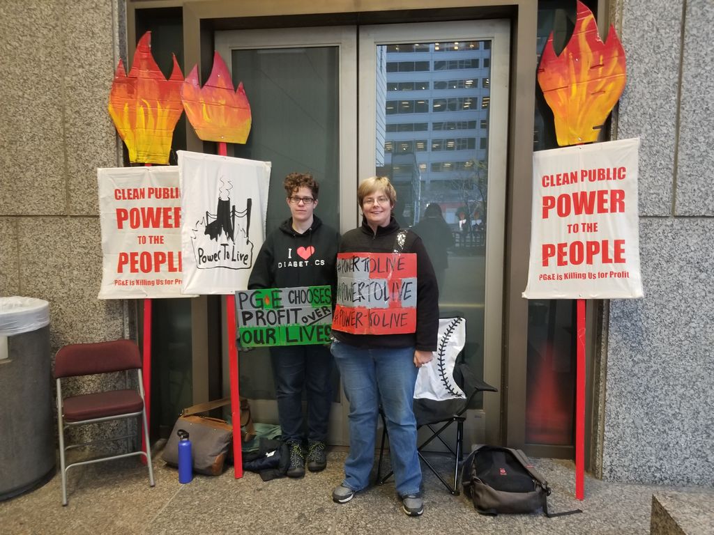 two activists stand in front of a door with sign