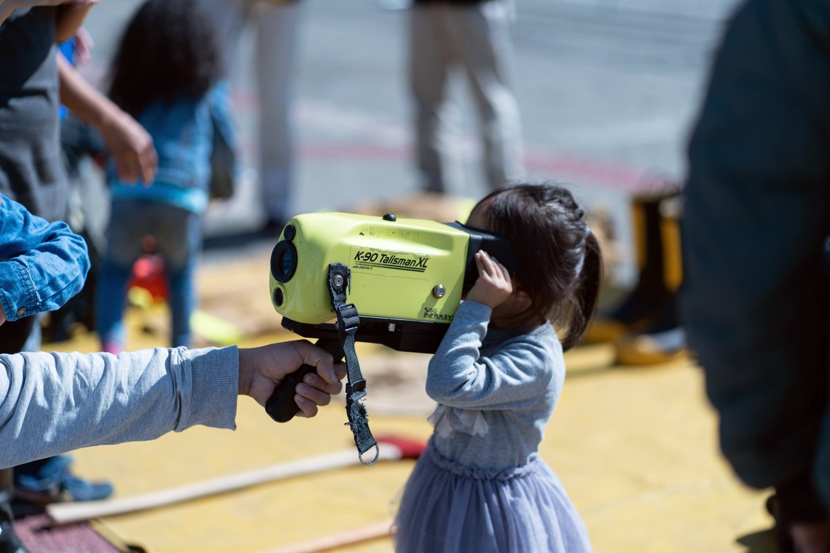 little girl looks through temperature viewer held by her dad