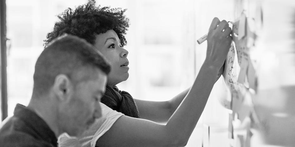 woman writing on sticky notes on board