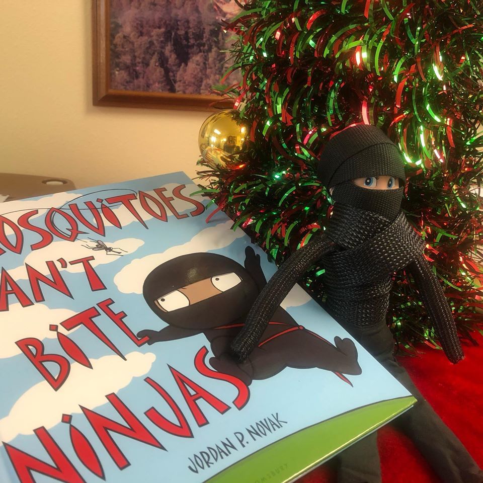 PascoMosquito's tweet photo. #Elfopictus is celebrating #InternationalNinjaDay cozied up next to the tree reading “Mosquitoes Can’t Bite Ninjas” https://t.co/Cx9s00rpta