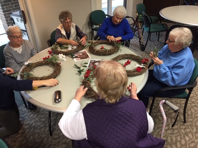 In remembrance of their beloved friend Ruth Curtis, residents came together at Manor &amp; Villages to make Christmas wreathes. Ruth always decorated her door for the holidays and loved crafting with her friends. Ruth will forever be greatly loved by everyone who knew her.