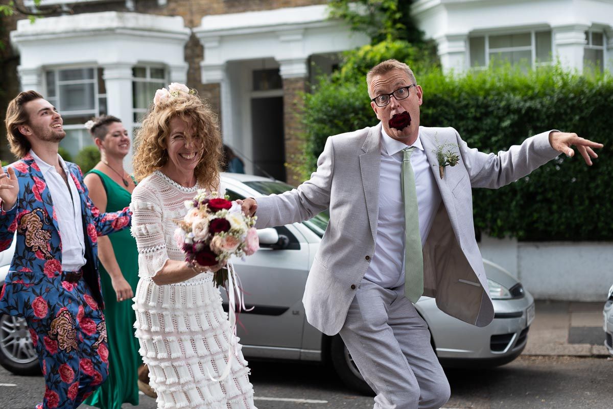 Will and Kitty enjoying their Wedding Procession from @CoLQueensPark #QueensParkLondon to @HugosQP. Will, ever the improviser, repurposed his detached Rose Pinhole as a comical mouth prop. #weddingphotographer #weddingphotographers #weddingphotographeruk #lewesweddingphotographer