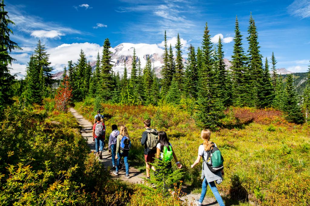 students hike on trail with mt. rainier in background