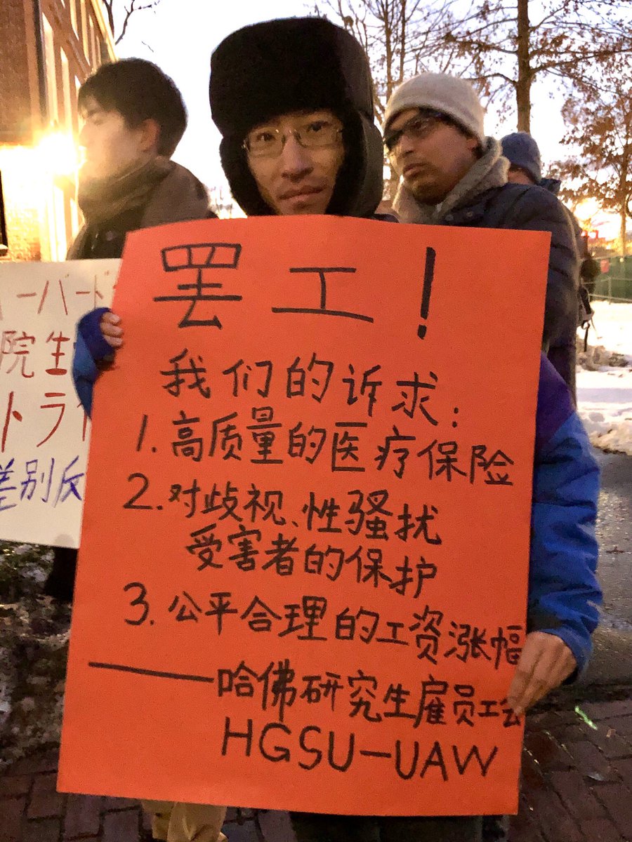 Protester with a hat holding a sign in Mandarin Chinese that says: STRIKE! Our demands: 1) good health care, 2) protecting victims of sexual harassment, and 3) fair wages. -- Harvard graduate student Union