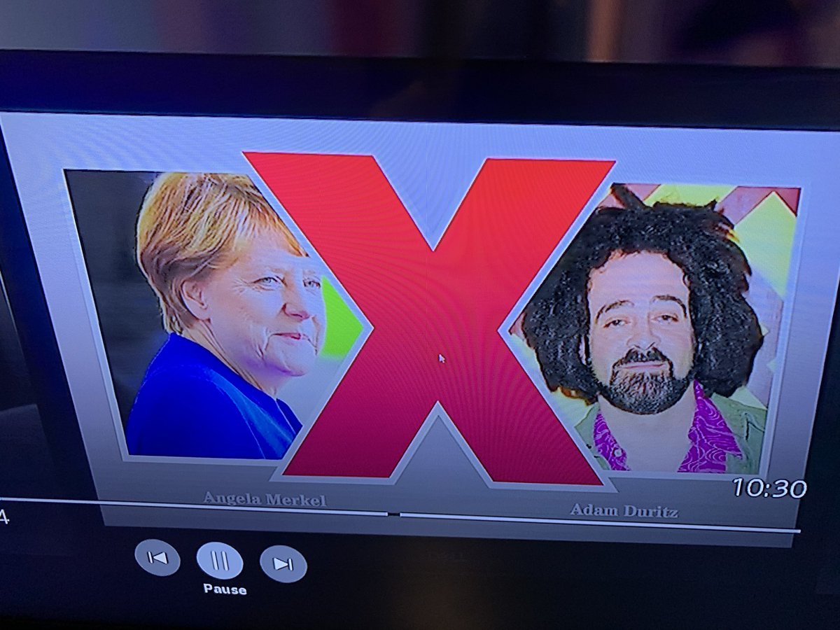 Angela Merkel and Adam duritz on a screen with a big X for some reason.