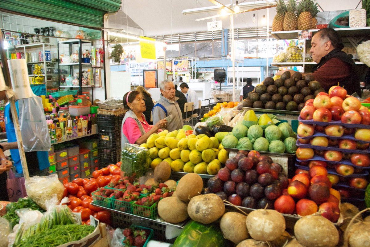 An old couple buying fruits and vegetables from a vendor in a traditional market