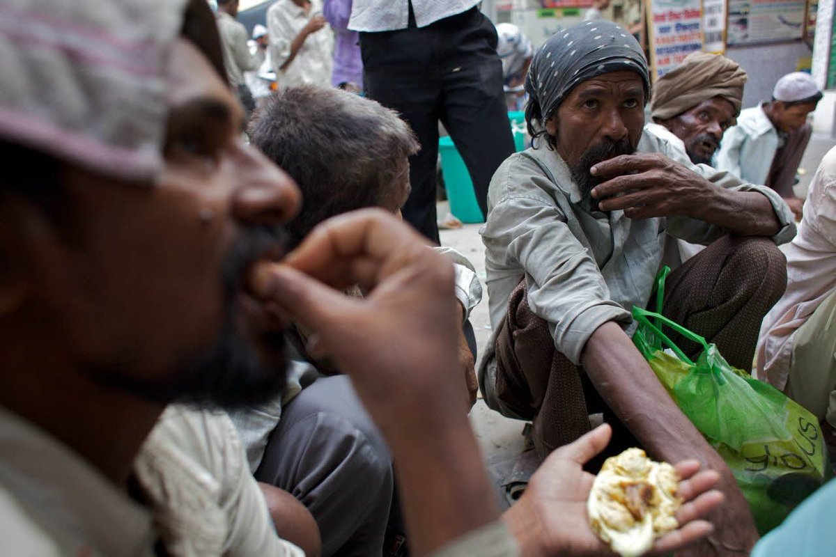 Men squatting eating bread
