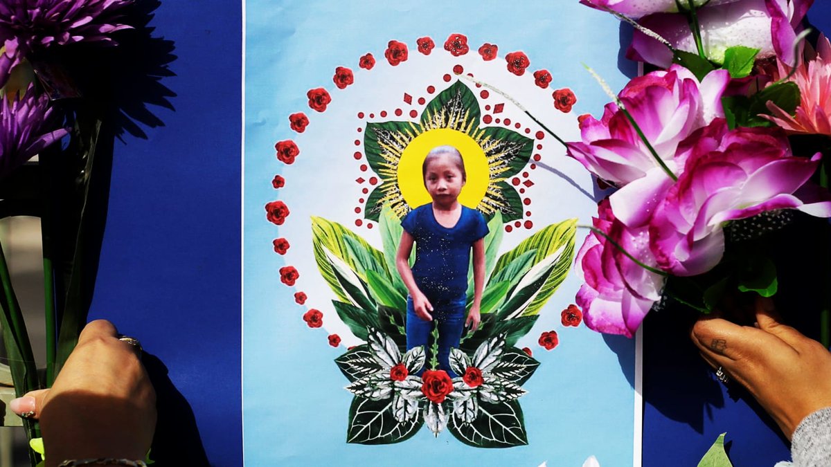 Women placing flowers next to a collage of Jakelin.