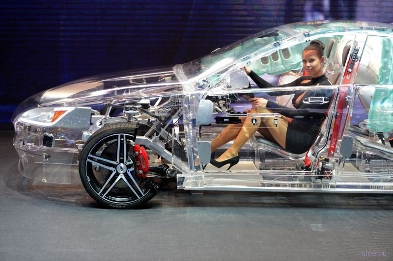 stickerride's tweet image. A model sits in a acrylic glass car body that shows the car technik at the IAA international automobile show.