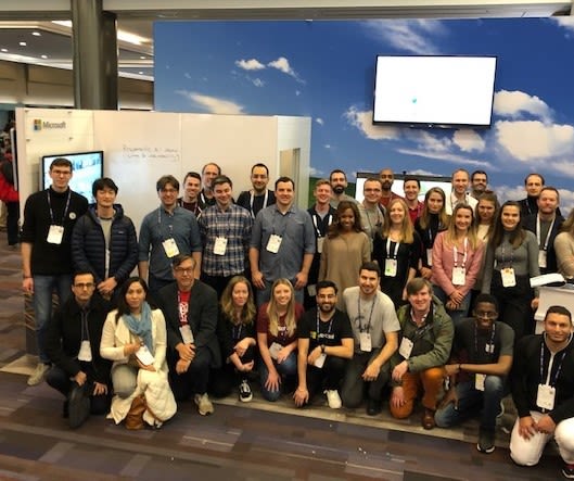 A group photo of over 30 Microsoft employees at NeurIPS 2019 in front of the Microsoft booth.