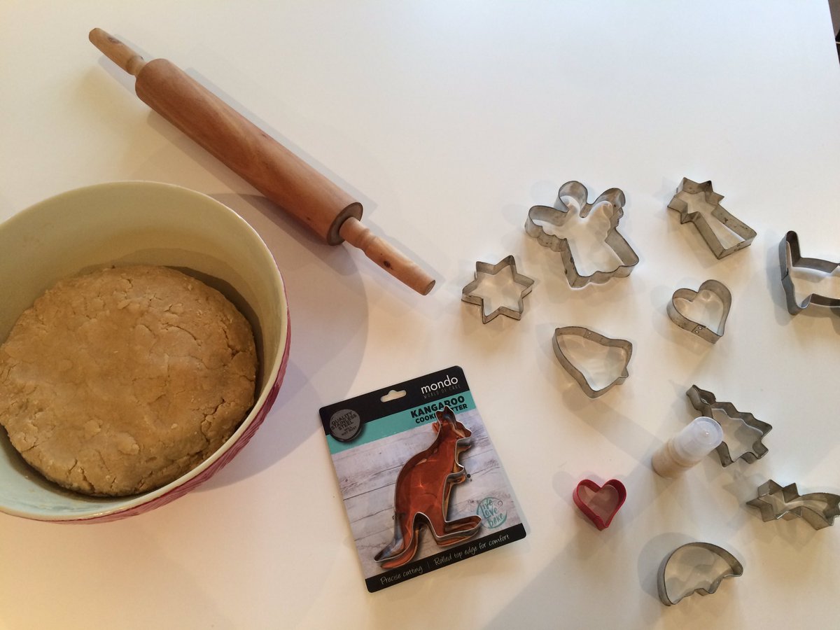 Gingerbread dough in bowl, rolling pin, various biscuit cutters including a kangaroo and Christmas themed ones.