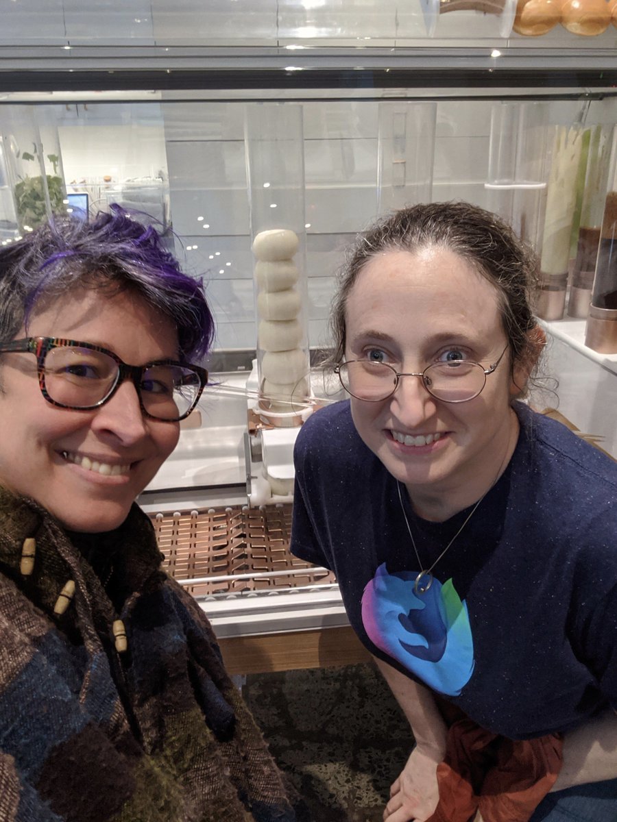 Two smiling women in front of machinery