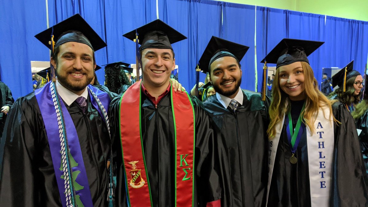 Four students in caps and gowns standing backstage.