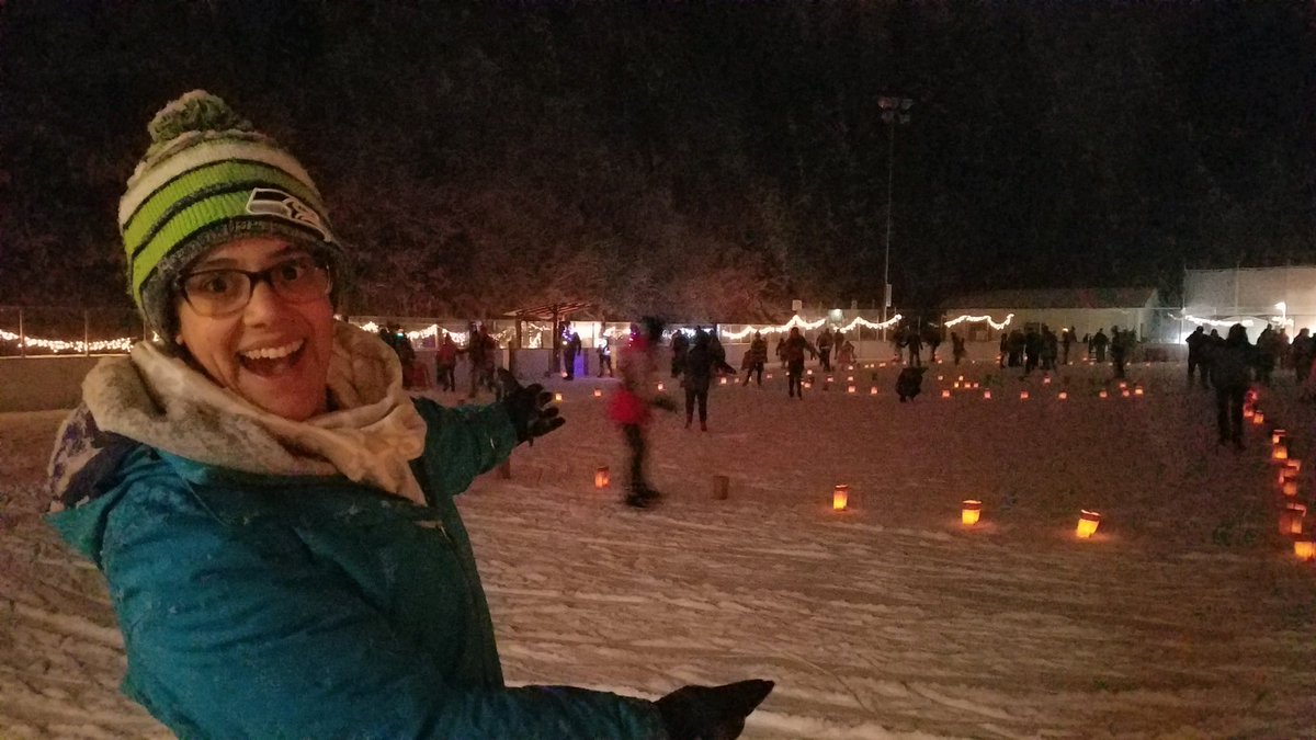 Standing on an ice rink in the snow. There are luminarias too.