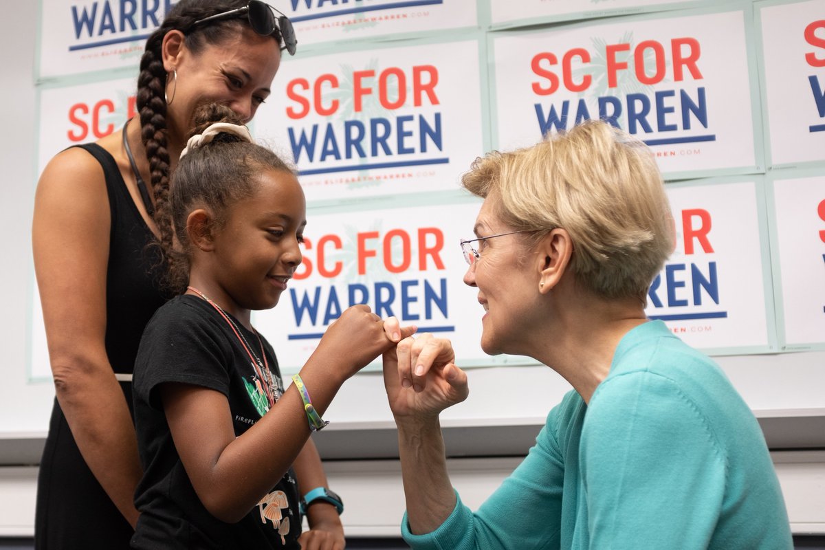 Elizabeth Warren makes a pinky promise with a young child.