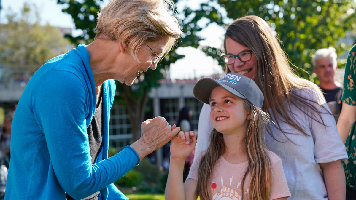 Elizabeth Warren makes a pinky promise with a young child.